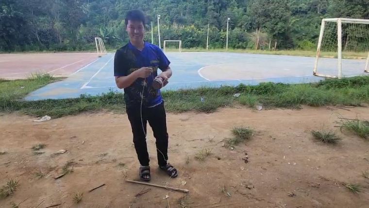 ชาวบ้านพันเชือกรอบลูกข่างไม้ก่อนเหวี่ยงลงลานดิน